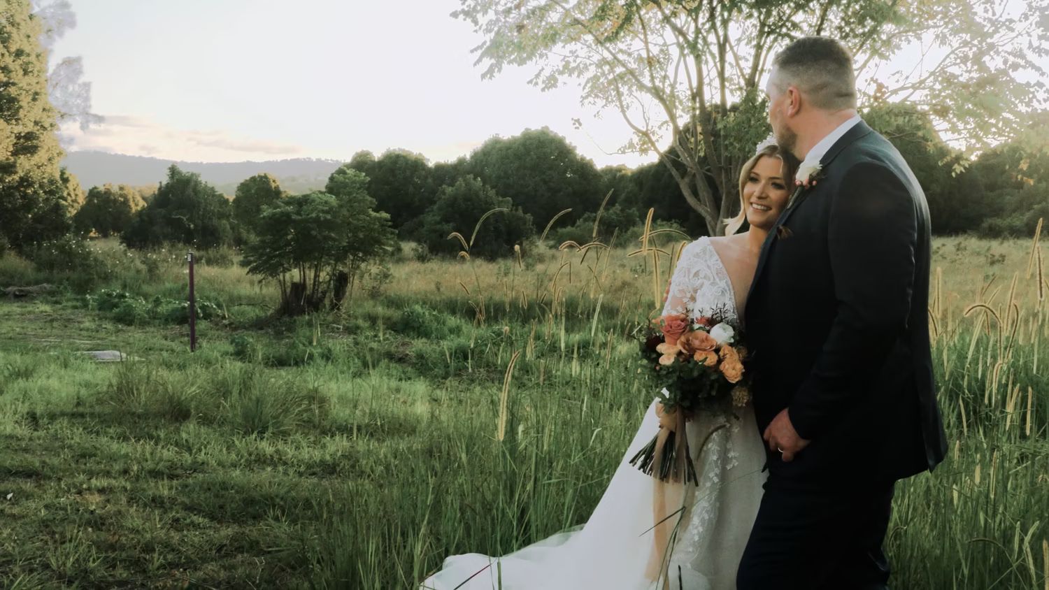Bride and groom standing together in a grassy countryside setting